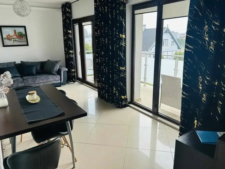 Salon z kanapą, stołem i wyjściem na balkon — Apartament 4, Zatoka Cydrowa w Stegnie